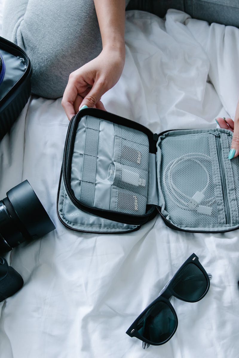 Traveler organizing essentials including a camera and packing cubes on a hotel bed.